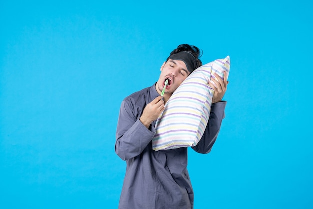 vue de face jeune homme en pyjama se brosser les dents et essayer de dormir sur fond bleu cauchemar couleur reste sillage humain propre rêve lit nuit