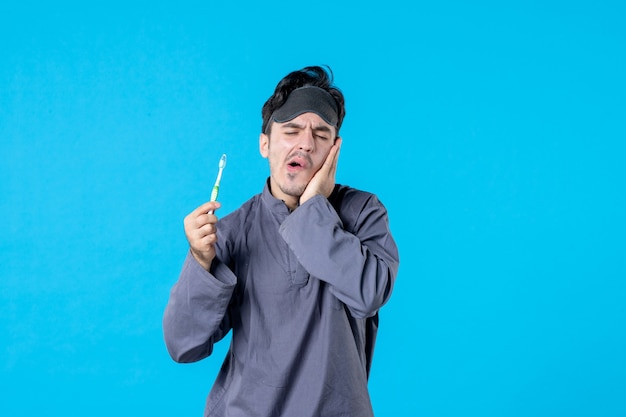 vue de face jeune homme en pyjama vérifiant ses dents sur fond bleu rêve cauchemar couleur réveil propre lit humain