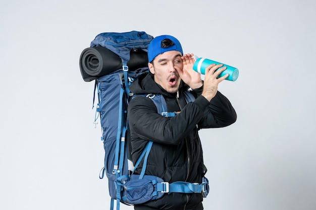 vue de face jeune homme avec sac à dos tenant un thermos vide sur fond blanc camp de montagne nature campagne neige froide air forestier