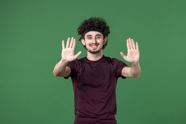 vue de face jeune homme souriant et demandant d'arrêter sur fond vert couleur sport gym entraînement athlète en cours d'exécution mode de vie