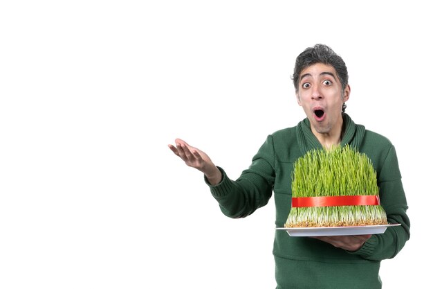 Vue de face d'un jeune homme surpris tenant un grand novruz semeni traditionnel sur fond blanc origine ethnique printemps danseur horizontal couleurs interprète concept ethnique