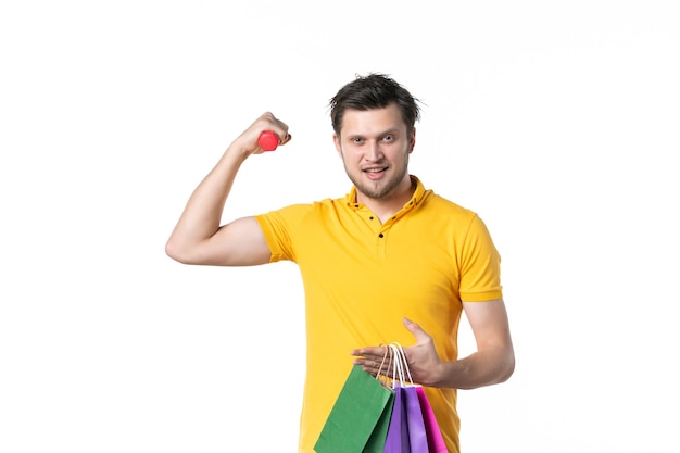 Vue de face jeune homme tenant des haltères et des paquets sur fond blanc uniforme humain travail argent couleur shopping vendeur travailleur