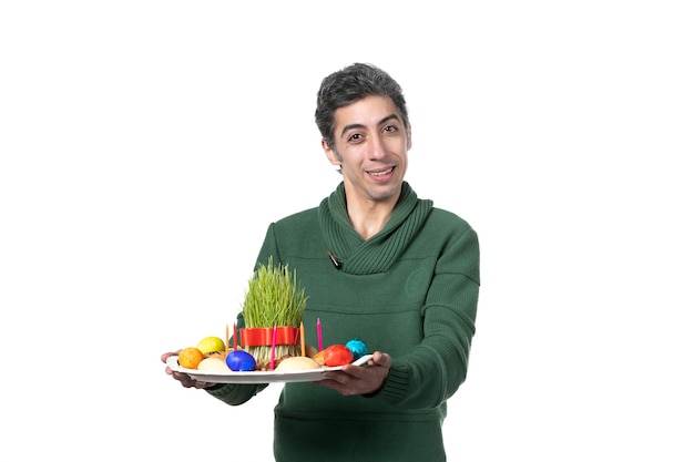 vue de face jeune homme tenant novruz honca avec semeni et bonbons sur fond blanc origine ethnique printemps couleurs interprète horizontal