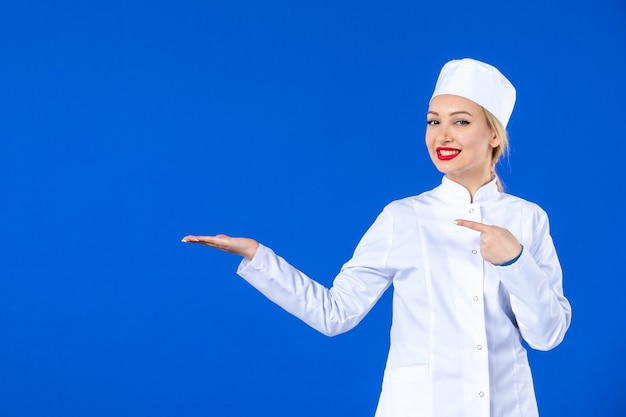 vue de face de la jeune infirmière en costume médical sur le mur bleu