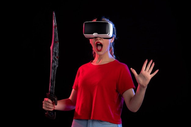 Vue de face d'une jolie femme jouant au vr avec une épée sombre