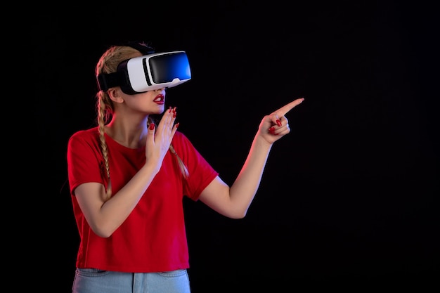 Vue de face d'une jolie femme jouant à la réalité virtuelle dans l'obscurité