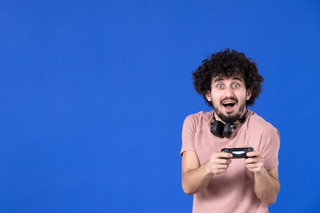 vue de face joueur masculin jouant à un jeu vidéo avec manette de jeu fond bleu jeunesse joie adolescent soccer canapé joueur virtuel adulte