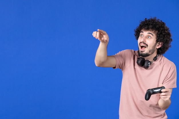 vue de face joueur masculin jouant à un jeu vidéo avec manette de jeu sur fond bleu joueur virtuel gagnant joie des jeunes adolescent jeune football canapé adulte