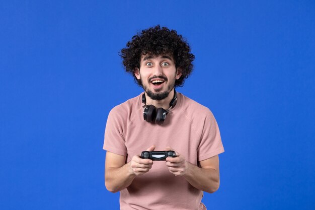 Vue de face joueur masculin jouant à un jeu vidéo avec manette de jeu sur fond bleu vidéo adulte virtuelle gagnant joueur de joie jeune adolescent de football