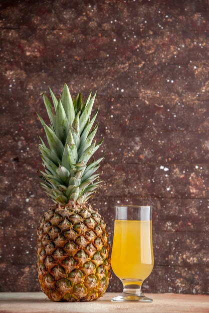 vue de face jus d'ananas frais en verre sur fond marron