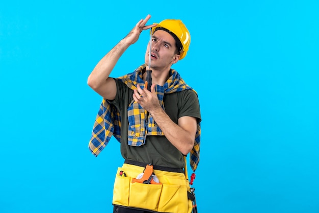 Vue de face mâle constructeur en casque tenant un tournevis sur le fond bleu architecture plate constructeur maison emploi travailleur du bâtiment