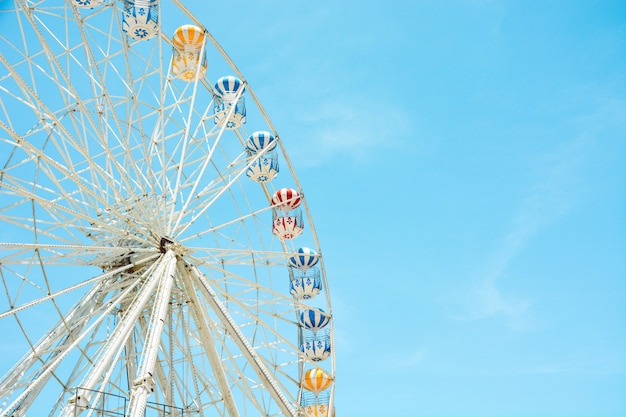 Vue de face de la moitié de la grande roue colorée rétro au parc d&#39;attractions sur fond de ciel bleu