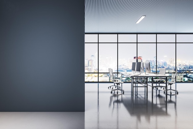 Vue de face sur un mur noir vierge dans un bureau à espace ouvert de nuit avec tables de travail et chaises ordinateurs modernes et mur transparent avec vue nocturne sur la ville et lampadaires rendu 3D maquette