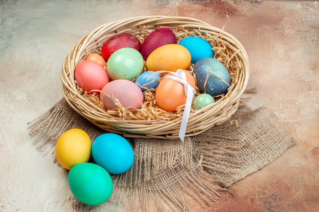 vue de face oeufs de pâques colorés à l'intérieur du panier sur une surface claire