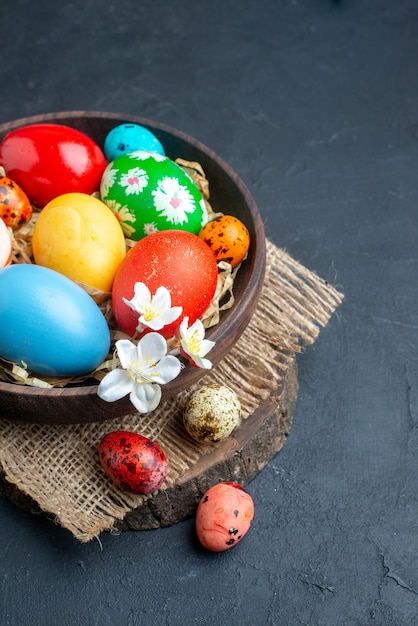 vue de face oeufs de pâques colorés à l'intérieur de la plaque avec de la paille sur une surface sombre ornée de vacances colorées groupe de printemps concept multi