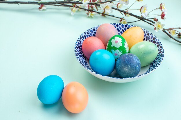 Vue de face des oeufs de pâques colorés à l'intérieur de la plaque sur la surface bleue printemps orné de couleurs ethniques vacances Pâques coloré