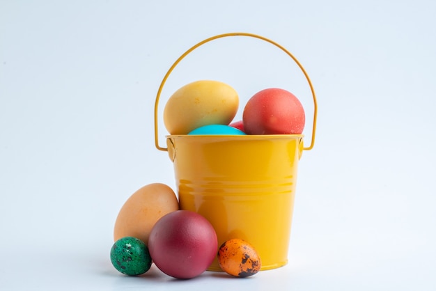 Vue de face des oeufs peints de couleur à l'intérieur du panier sur fond blanc vacances colorées de printemps novruz orné