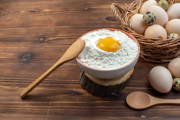 vue de face des œufs de poule à l'intérieur du panier avec de la farine sur une surface brune