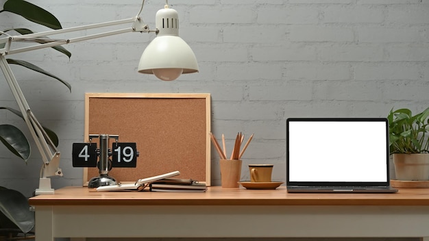 Vue de face d'un ordinateur portable avec lampe d'affichage vide, tasse à café et planche sur un bureau en bois