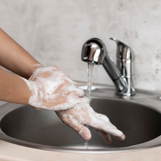 Photo vue de face personne se laver les mains dans un évier