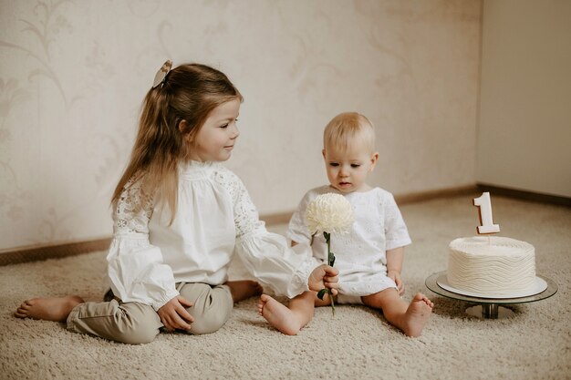 Vue de face d'une petite fille adorable donnant une fleur à sa jeune sœur pour son premier anniversaire