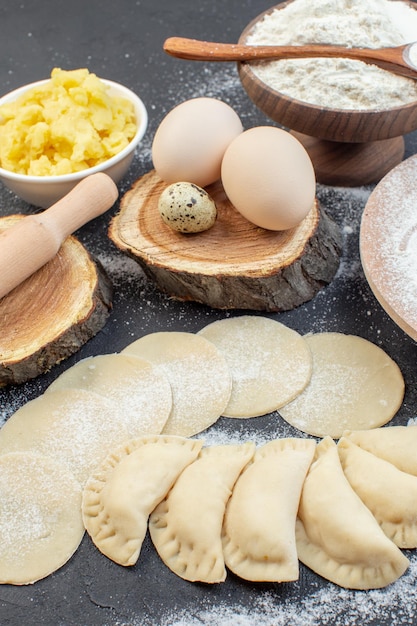 vue de face des petits pains aux pommes de terre crues avec des œufs purée de pommes de terre et de la farine sur fond sombre repas tarte biscuit four cuire la pâte cuisson