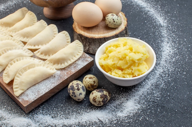 vue de face de petits petits pains crus avec de la farine de pommes de terre en purée et des œufs sur fond sombre gâteau de pâte à tarte cuire au four à biscuits à l'huile de poussière