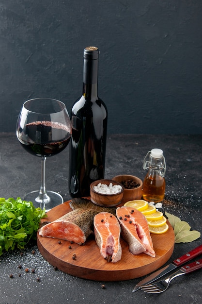 vue de face poisson frais avec bouteille de vin et assaisonnements sur fond sombre repas de fruits de mer nourriture repas eau viande de poisson océan salade mer