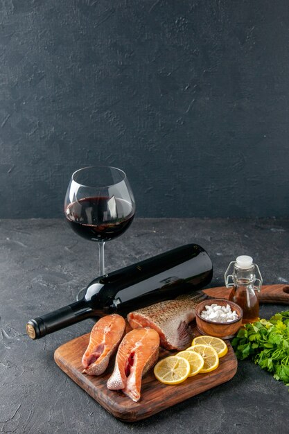 vue de face poisson frais avec des tranches de citron et une bouteille de vin sur le fond sombre salade de poisson eau viande océan mer repas dîner fruits de mer