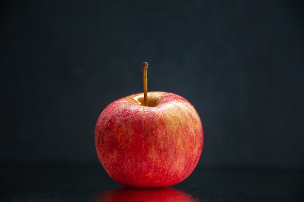 Vue de face d'une pomme fraîche rouge debout sur fond de vague sombre avec espace libre