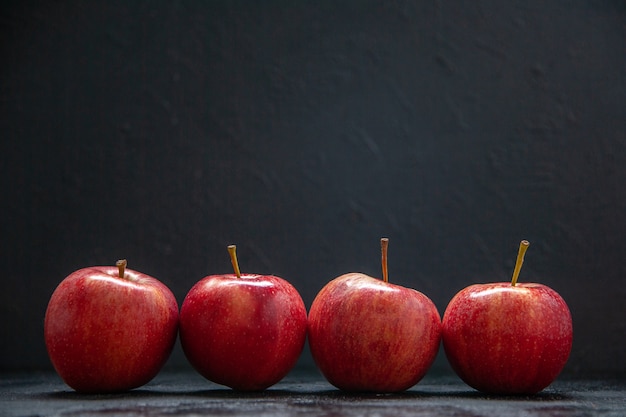 Vue de face de pommes fraîches rouges côte à côte sur fond de vague sombre