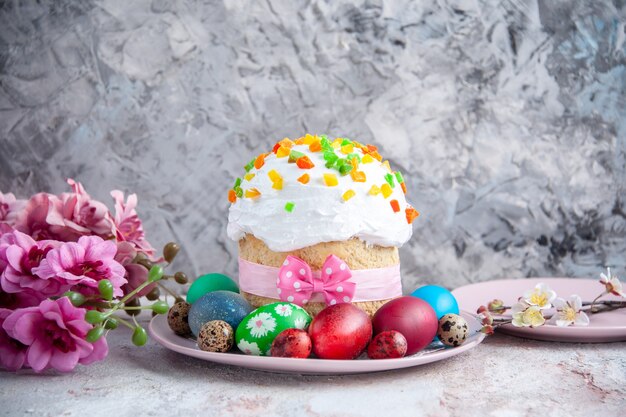 vue de face savoureux gâteau de pâques avec des œufs colorés à l'intérieur de la plaque sur une surface blanche tarte au printemps dessert sucré de pâques orné