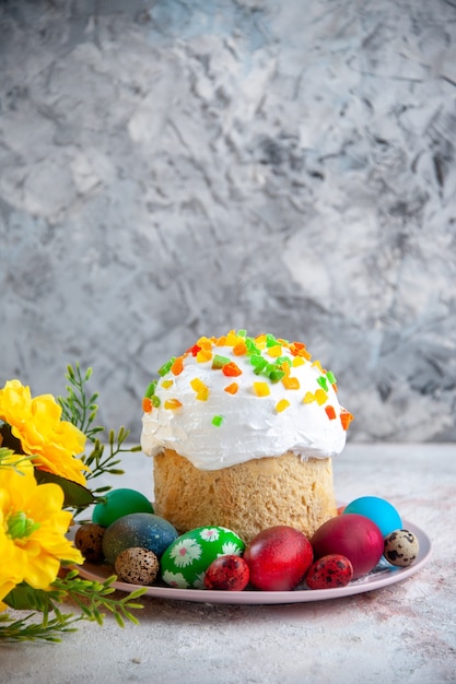 vue de face savoureux gâteau de pâques avec des œufs colorés à l'intérieur de la plaque sur une surface blanche tarte au printemps orné de bonbons colorés de pâques dessert