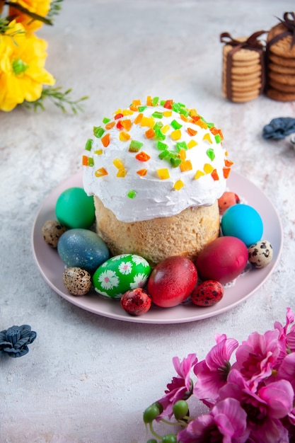 vue de face savoureux gâteau de pâques avec des œufs colorés à l'intérieur de la plaque sur une surface blanche tarte au printemps orné de dessert sucré de pâques