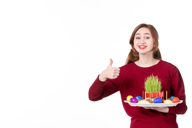 vue de face souriante jeune femme tenant honca avec des bonbons semeni et novruz sur fond blanc interprète ethnique couleurs famille printemps ethnicité concept de vacances