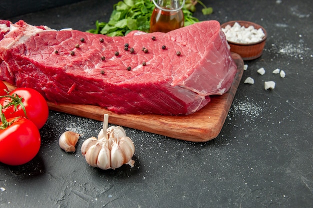 vue de face tranche de viande crue avec des verts et des tomates sur le fond sombre plat de cuisson nourriture viande dîner repas boucher barbecue couleur