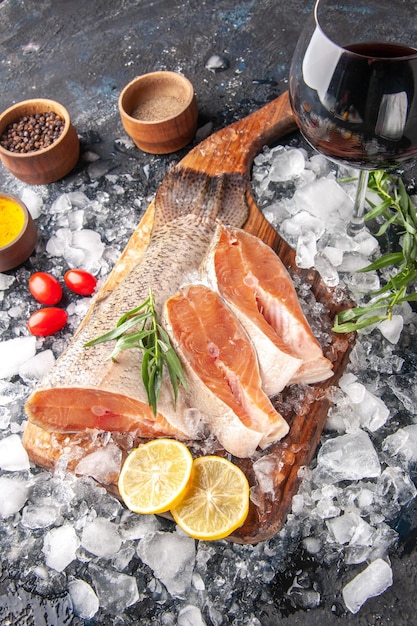 Vue de face des tranches de poisson frais avec du vin et de la glace sur fond sombre restaurant dîner repas fruits de mer santé océan nourriture viande