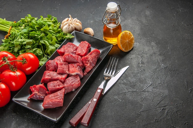 vue de face des tranches de viande fraîche avec des verts et des tomates sur fond sombre repas dîner viande animal barbecue nourriture boucherie salade