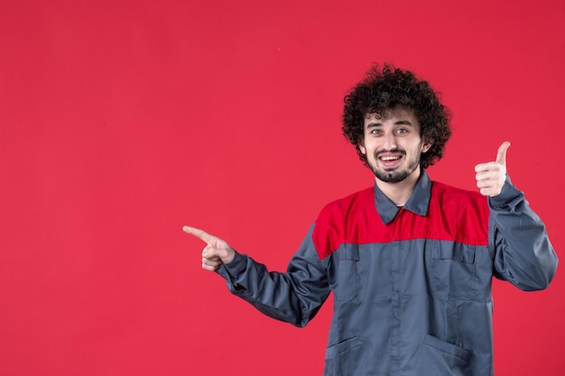 Vue de face travailleur masculin en uniforme sur fond rouge couleur de travail uniforme travailleur instrument maison photo