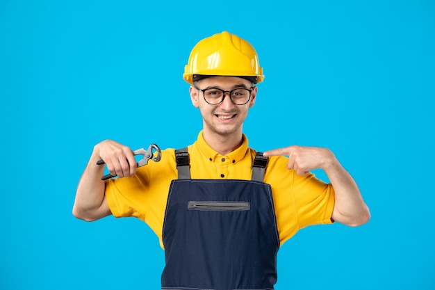 Vue de face travailleur masculin en uniforme jaune avec des pinces sur bleu