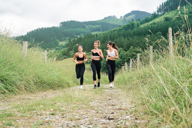 Vue de face trois belles femmes qui traversent un chemin à travers une forêt