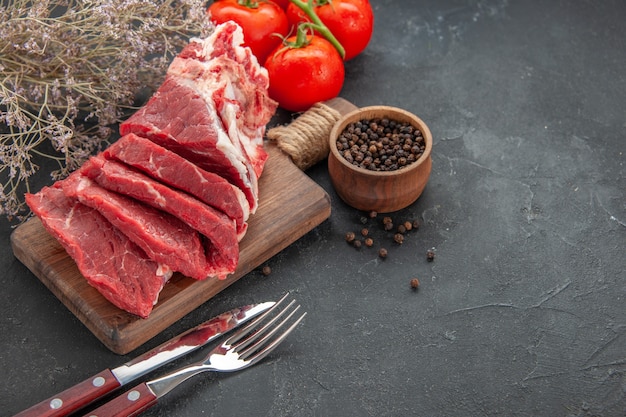 vue de face de la viande fraîche en tranches avec du poivre et des tomates sur fond sombre viande animal barbecue dîner nourriture couleur repas boucher