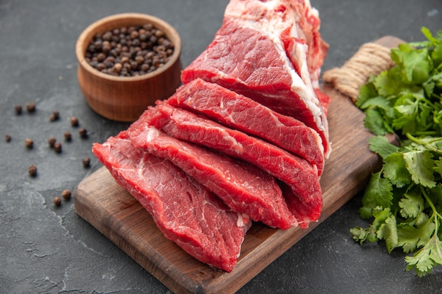 vue de face de la viande fraîche en tranches avec des légumes verts sur le fond sombre de la viande des animaux repas barbecue couleur boucher nourriture