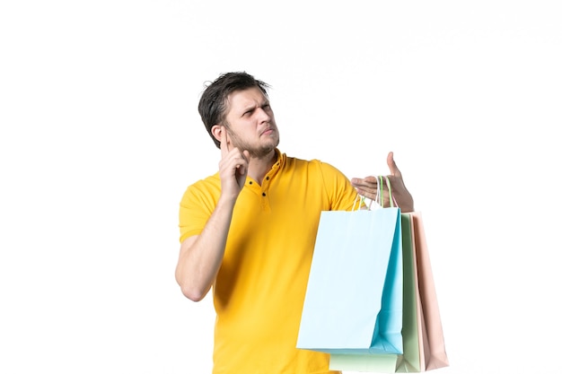 Vue de face young male holding shopping packages sur un fond blanc couleurs gym travail vendeur uniforme shopping santé argent