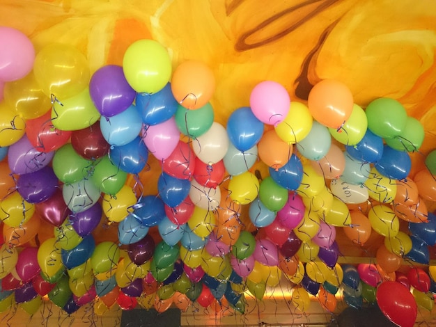 Photo vue à faible angle des ballons d'hélium multicolores contre le plafond