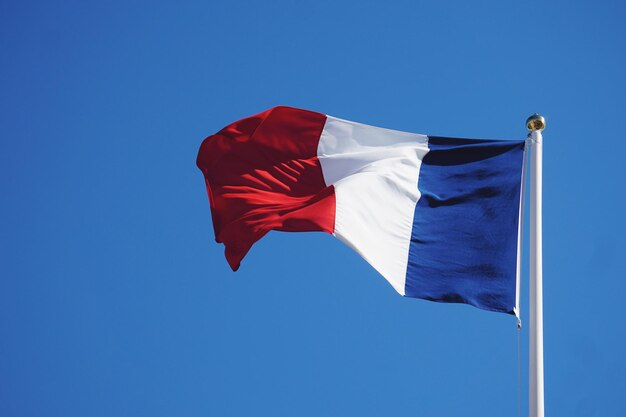 Vue à faible angle du drapeau français sur un ciel bleu clair