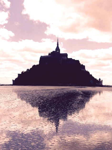 Photo vue à faible angle du mont saint-michel en mer contre le ciel au coucher du soleil