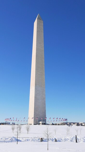 Vue à faible angle du monument de Washington sous la neige contre un ciel bleu clair