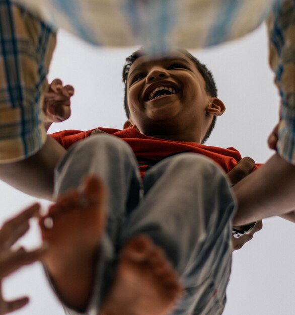 Photo vue à faible angle du père tenant son fils joyeux contre un ciel clair