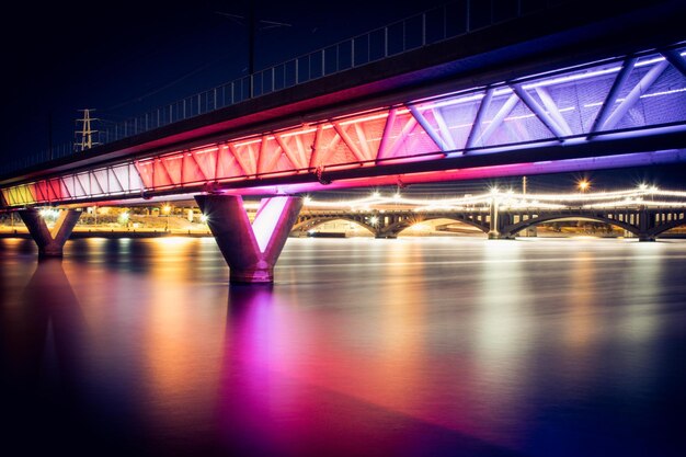 Photo vue à faible angle du pont éclairé sur la rivière la nuit